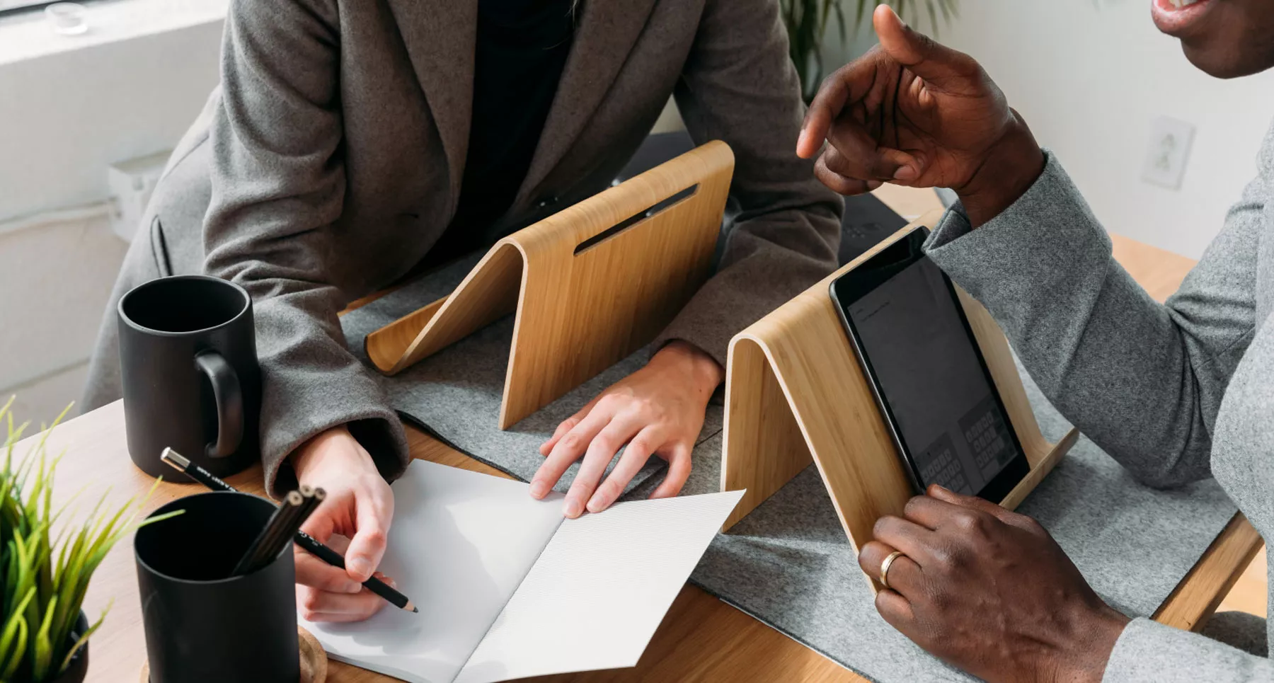 dos personas business debatiendo una con una tablet y otra anotando en un cuaderno